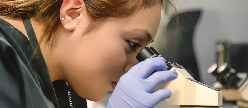 Medical assistant looking into microscope